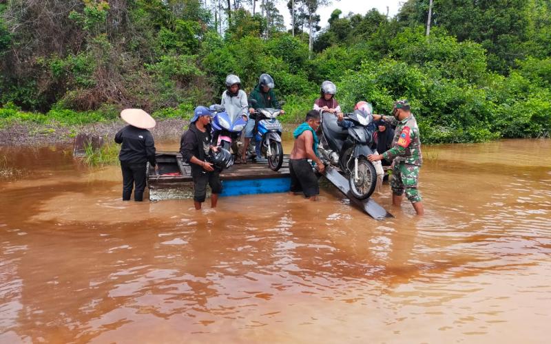 Dengan Sigap, Babinsa Bantu Seberangkan Motor dan Warga yang Melintas