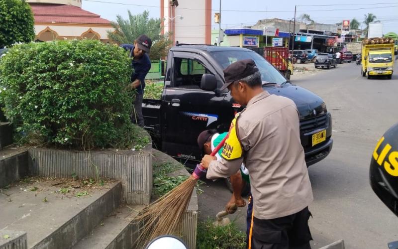 Wujudkan Lingkungan Bersih, Bhabinkamtibmas Bersama Perangkat Desa Gotong Royong Bersihkan Bundaran Giri Kencana