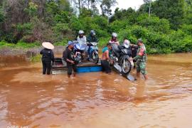 Dengan Sigap, Babinsa Bantu Seberangkan Motor dan Warga yang Melintas