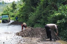 Sambang, Bhabinkamtibmas Polsek Rimbo Pengadang Bersihkan Material Longsor dan Timbun Jalan Berlubang